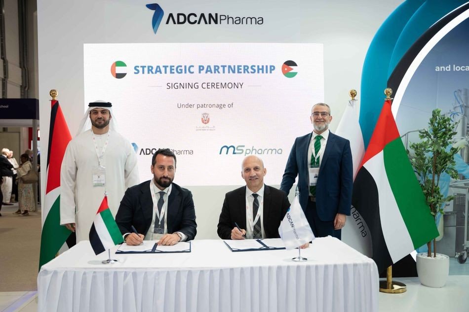 Two men in suits sign documents at a table in front of a backdrop reading Strategic Partnership Signing Ceremony with ADCAN Pharma and MS Pharma logos