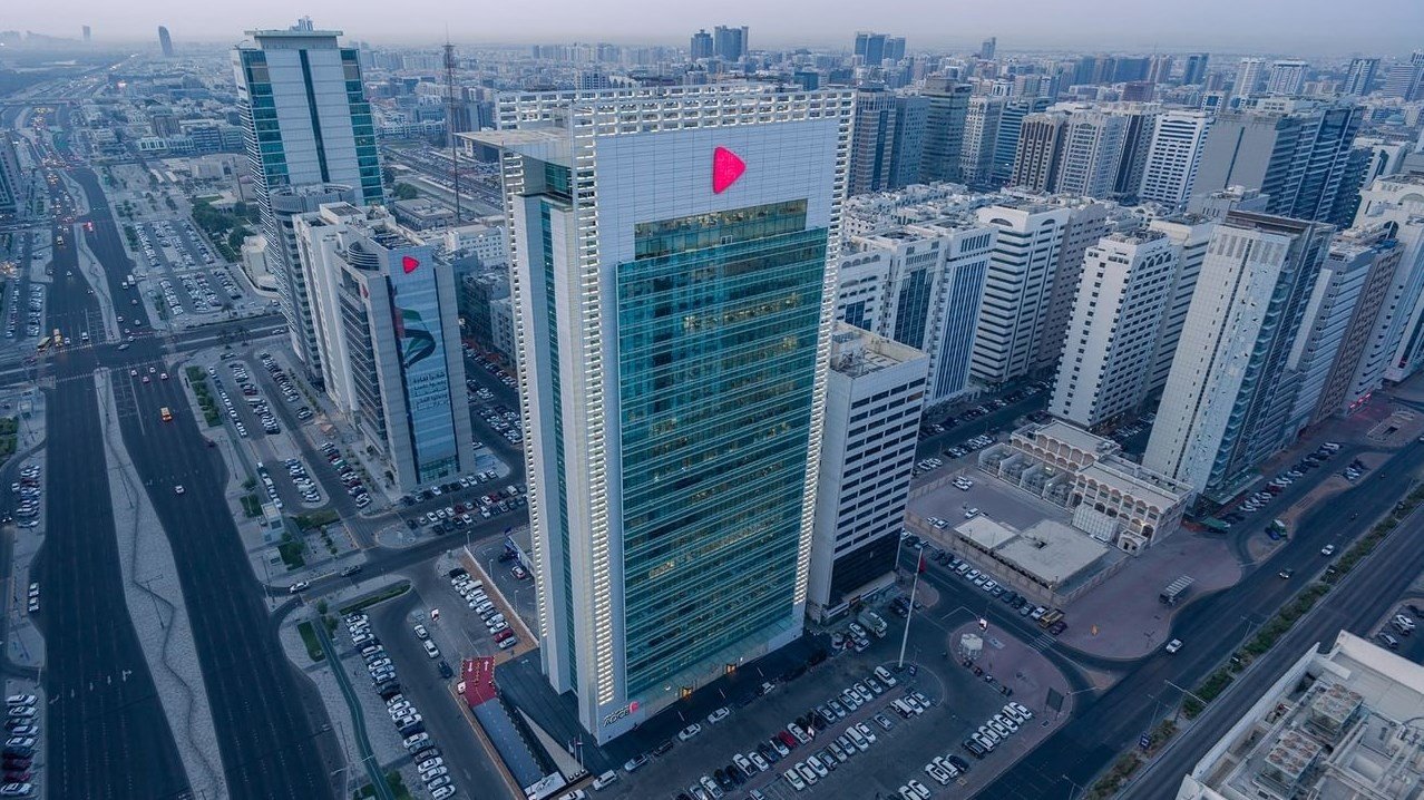 Aerial view of the ADCB headquarters tower among high-rise buildings and roads in Abu Dhabi