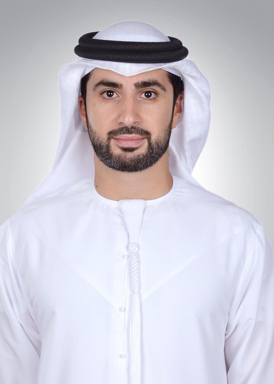 Portrait of Ali Alhosani in a white kandura and ghutra against a grey background