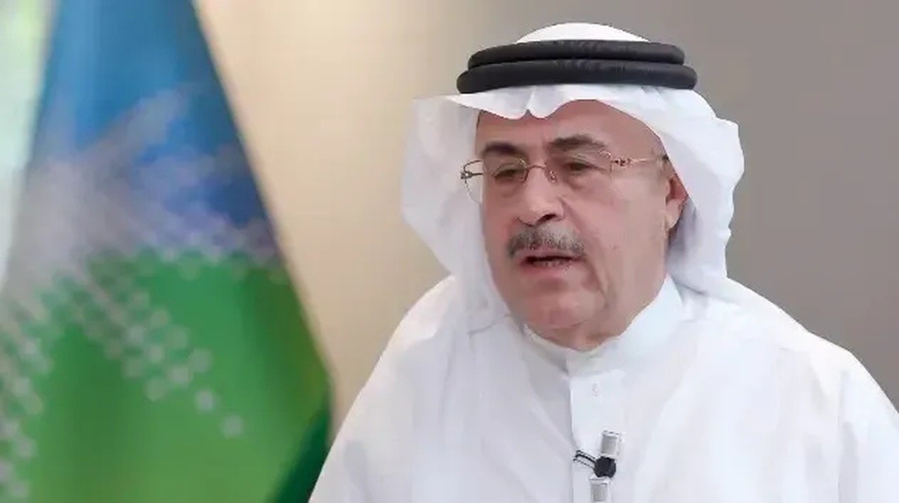 Aramco chief executive Amin Nasser in a white headdress speaks during a television interview in front of a Saudi Aramco flag