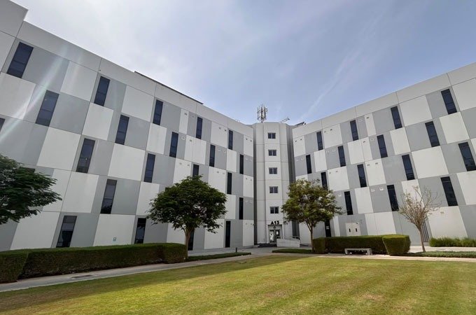 Multi-story workforce accommodation buildings around a lawn courtyard in the UAE