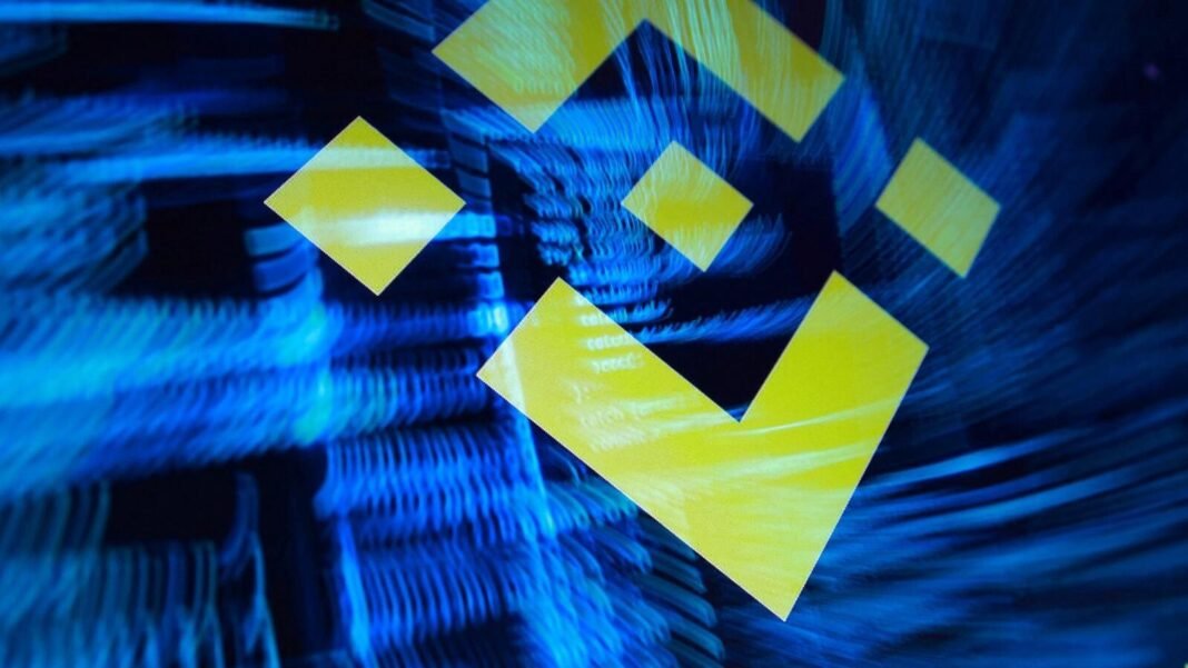 The Binance logo displayed over a blurred blue background in a photo illustration
