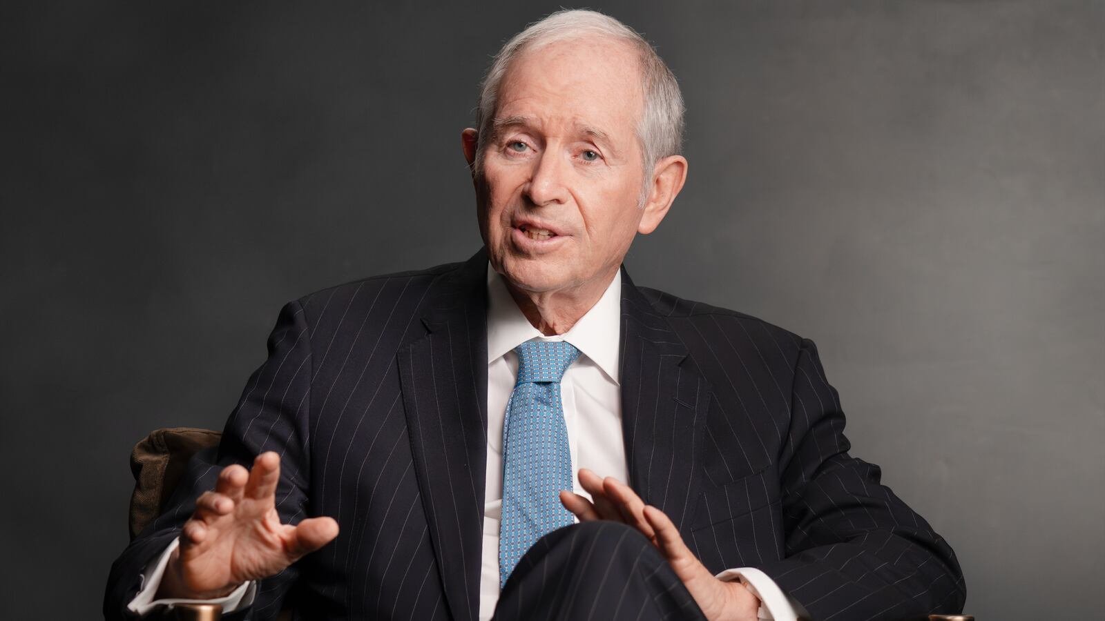 Blackstone chairman and chief executive Stephen Schwarzman gestures while seated in a dark suit