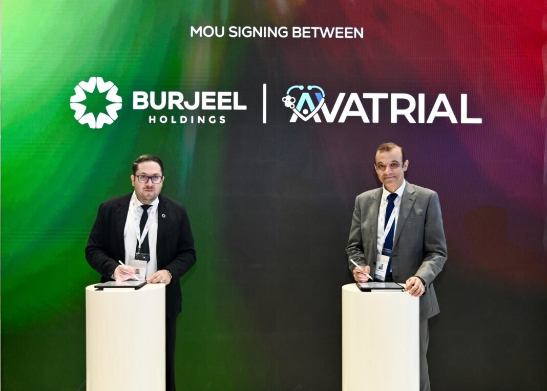 Two men in suits sign documents on tablets at white podiums in front of a screen reading MoU signing between Burjeel Holdings and Avatrial