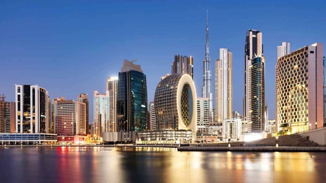 Towers in Business Bay along the Dubai Water Canal at dusk, with Burj Khalifa behind