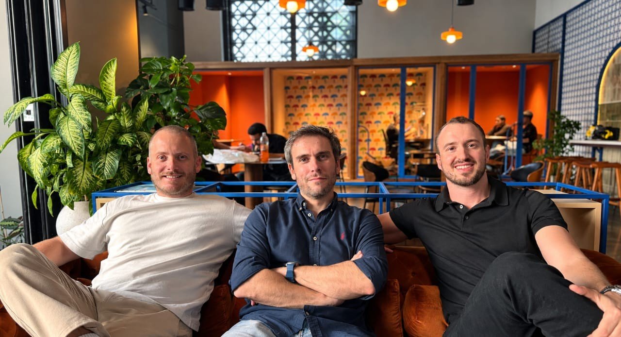 Three members of the CapQuest team seated together on a sofa in a cafe