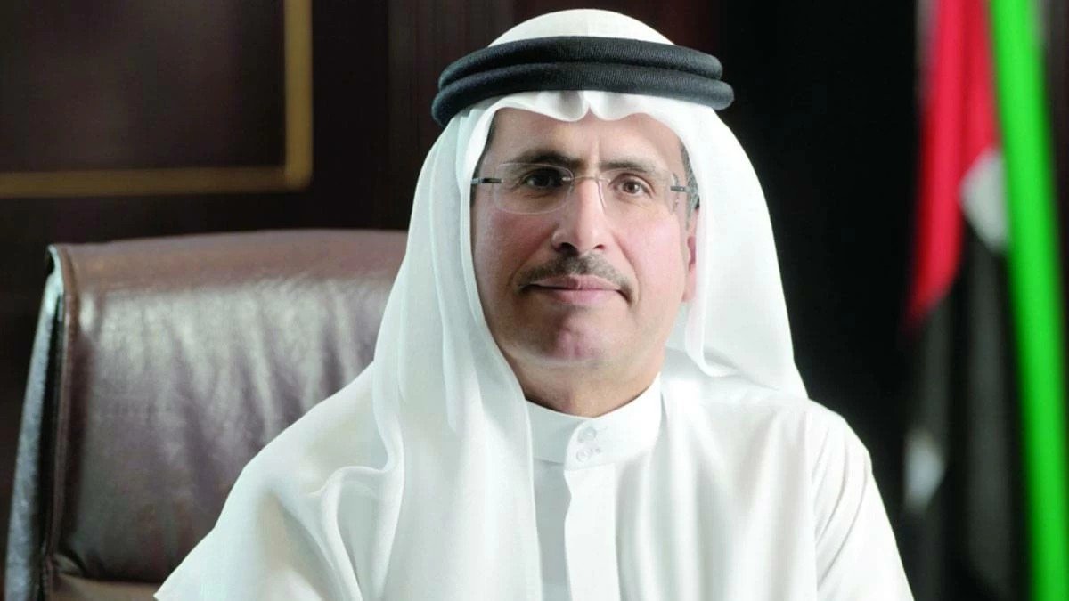 Portrait of DEWA Managing Director and CEO Saeed Mohammed Al Tayer seated at a desk beside a UAE flag