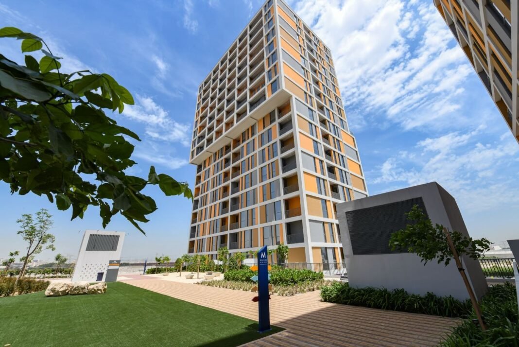 Residential tower with orange and white facade and landscaped gardens at Deyaar's Midtown community in Dubai