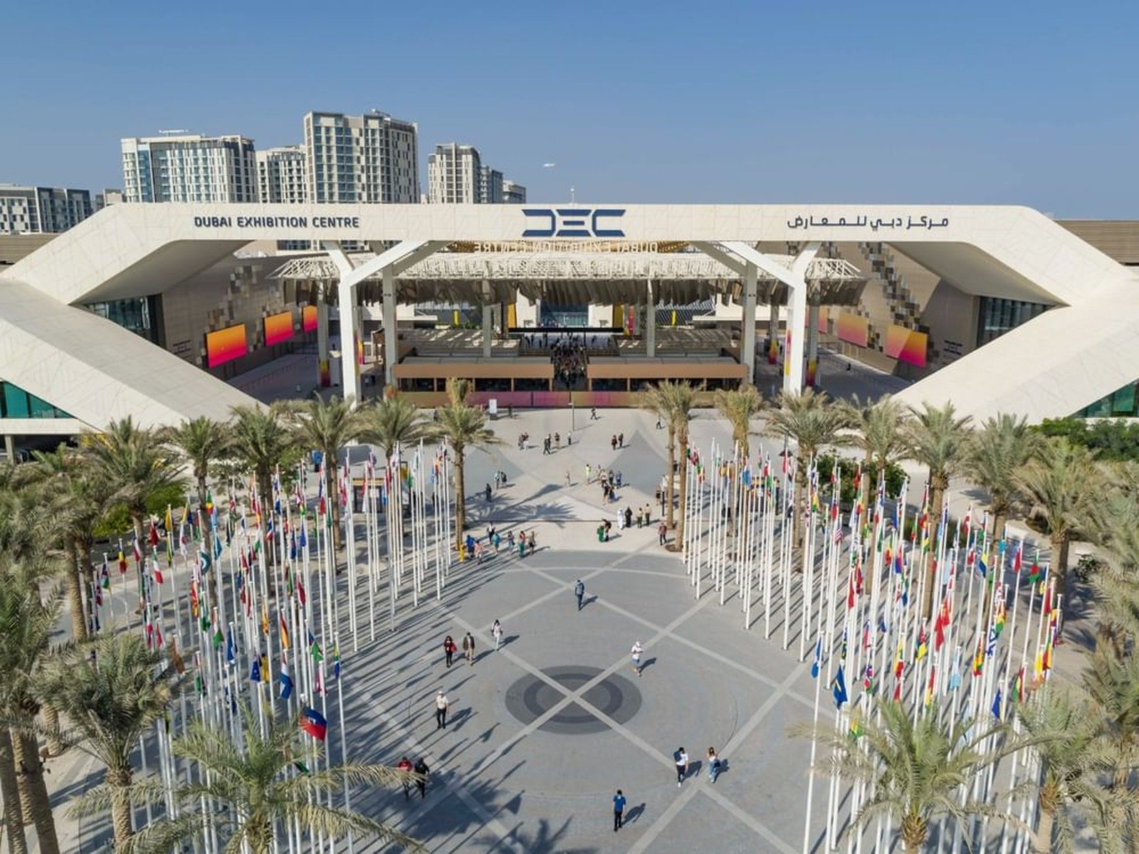 Exterior of the Dubai Exhibition Centre at Expo City Dubai with flagpoles in the plaza