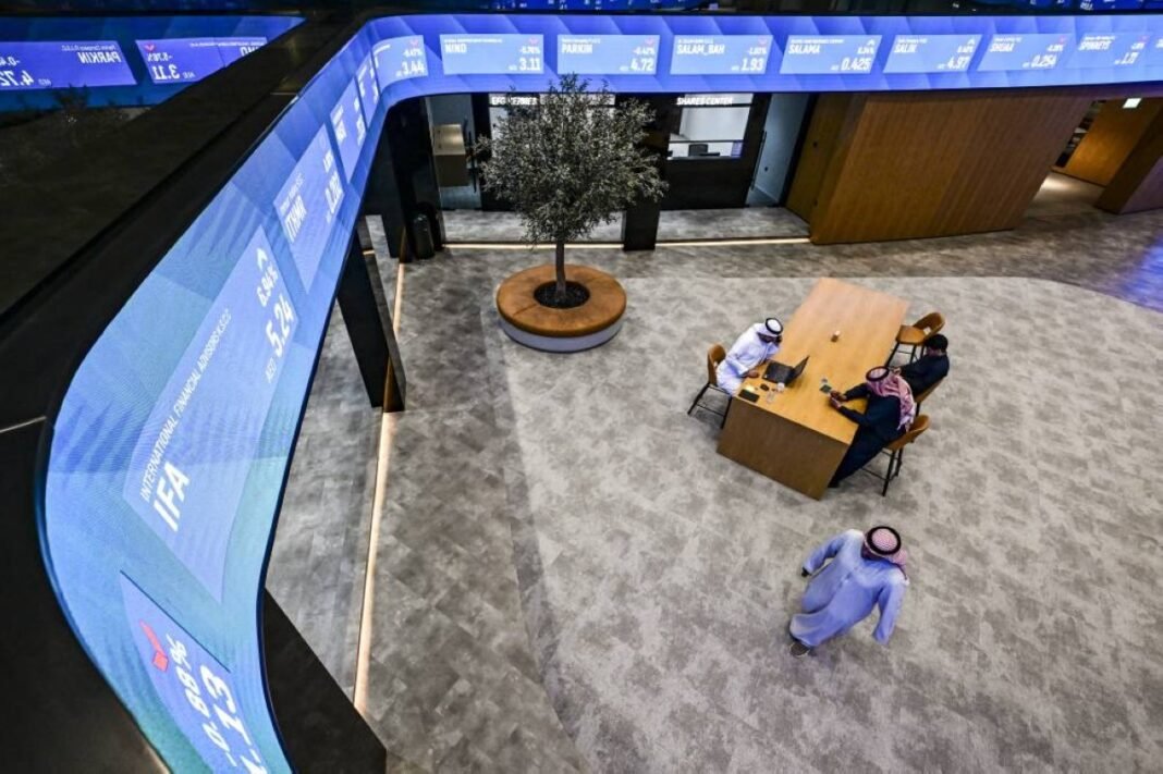 Investors in the trading hall of the Dubai Financial Market beneath a share price ticker