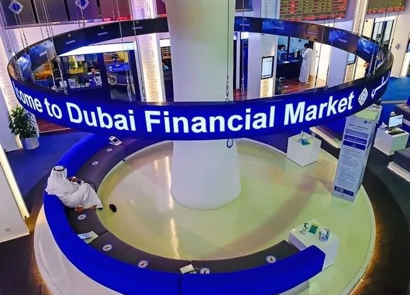 A blue Welcome to Dubai Financial Market sign ringing a seating area in the bourse's trading hall, with share price boards above