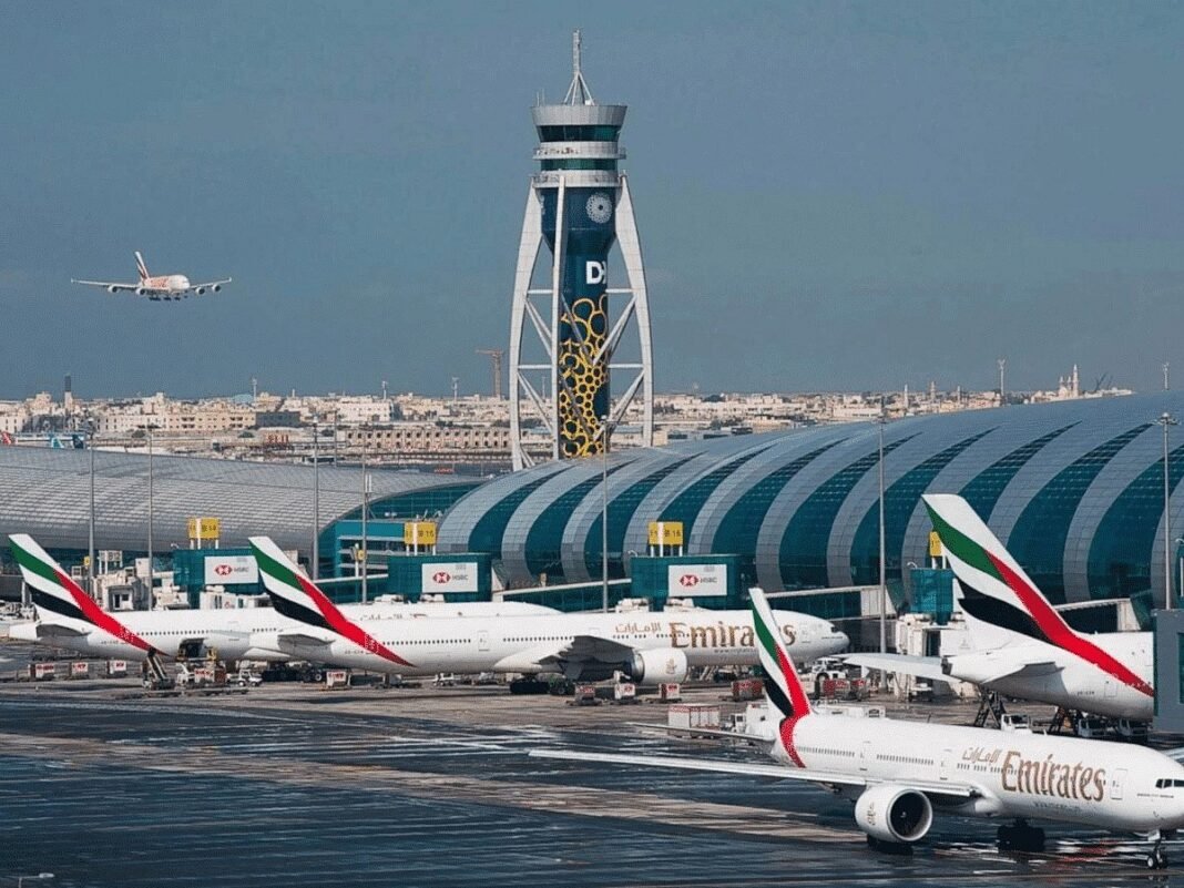 Emirates aircraft parked at Dubai International Airport as a plane comes in to land