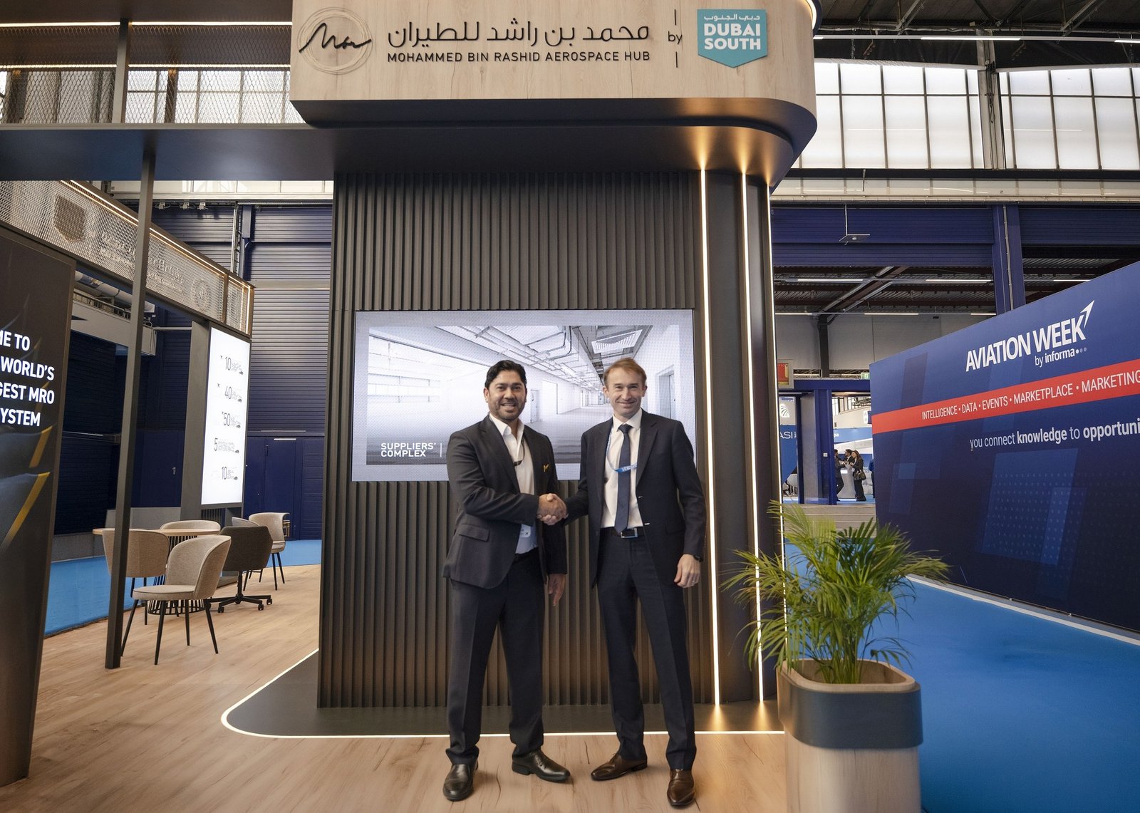 Two executives shake hands in front of the Mohammed Bin Rashid Aerospace Hub stand at the MRO Europe trade show