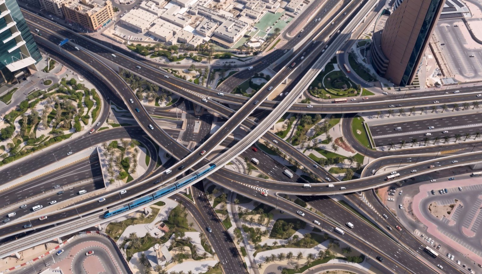 Aerial view of the multi-level World Trade Centre Roundabout interchange on Sheikh Zayed Road in Dubai, with a metro train crossing