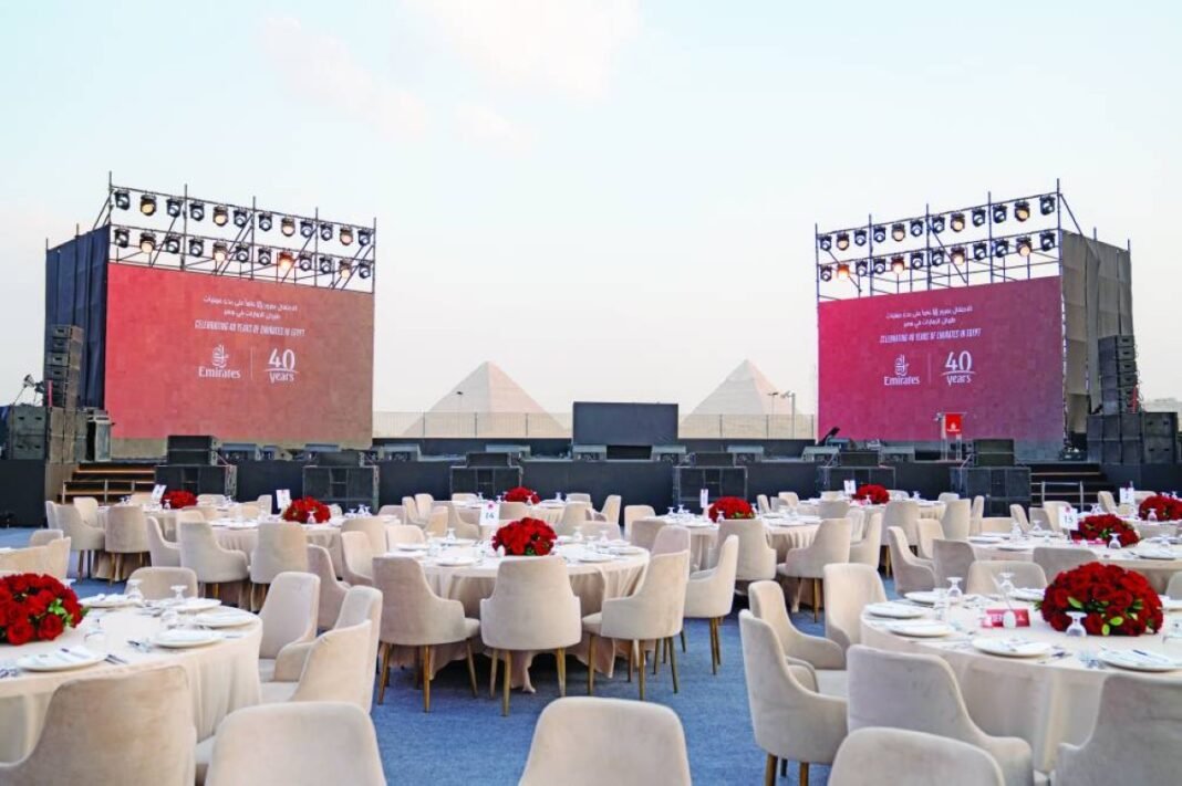 Dinner tables and stage screens reading Celebrating 40 years of Emirates in Egypt, with the Giza pyramids in the background