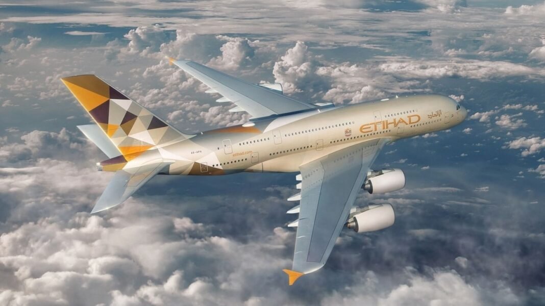 An Etihad Airways Airbus A380 in the airline's gold and white livery flying above clouds