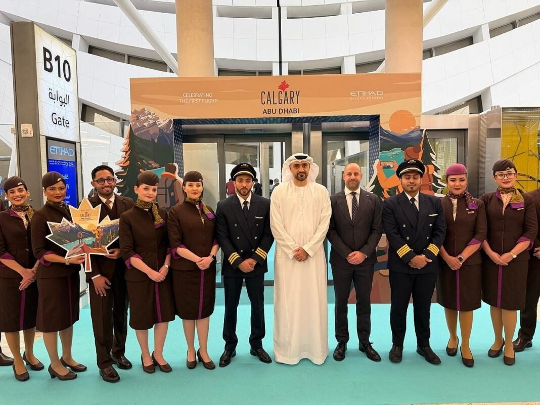 Etihad Airways crew and officials pose at gate B10 in Abu Dhabi under a banner celebrating the first Calgary flight