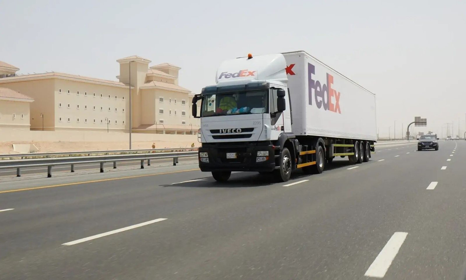 A white FedEx truck and trailer driving on a multi-lane desert highway