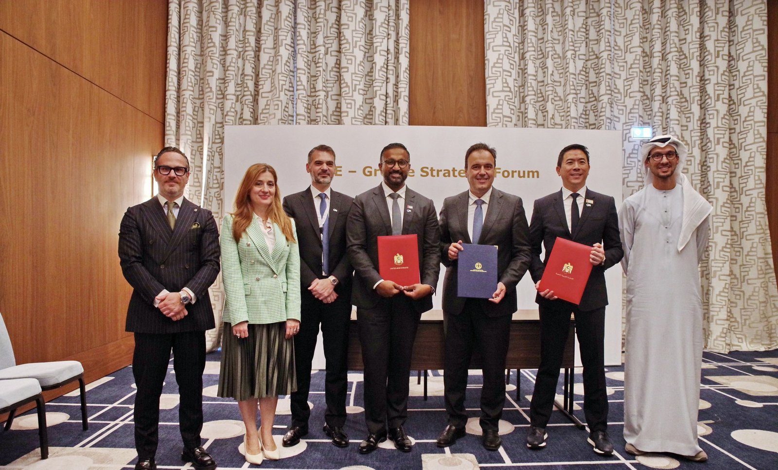 Executives holding signed agreement folders at the UAE-Greece Strategic Forum in Athens