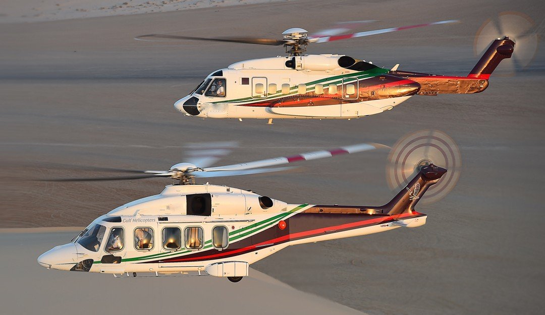 Two Gulf Helicopters aircraft flying low over desert terrain