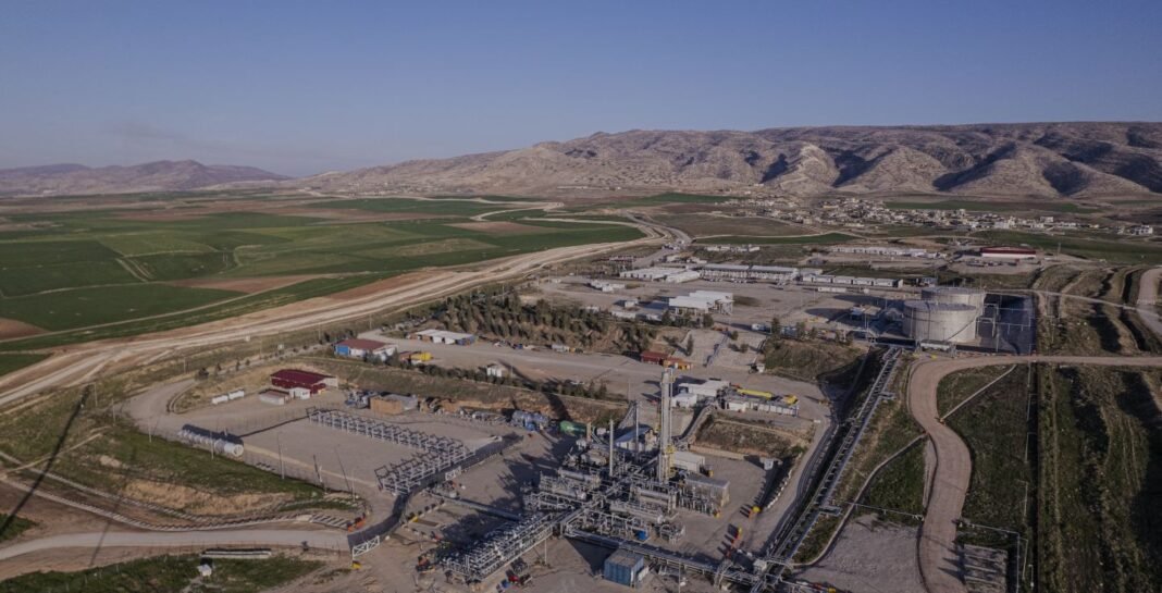 Aerial view of an oil production facility with storage tanks and pipework surrounded by farmland and hills in Iraq's Kurdistan Region