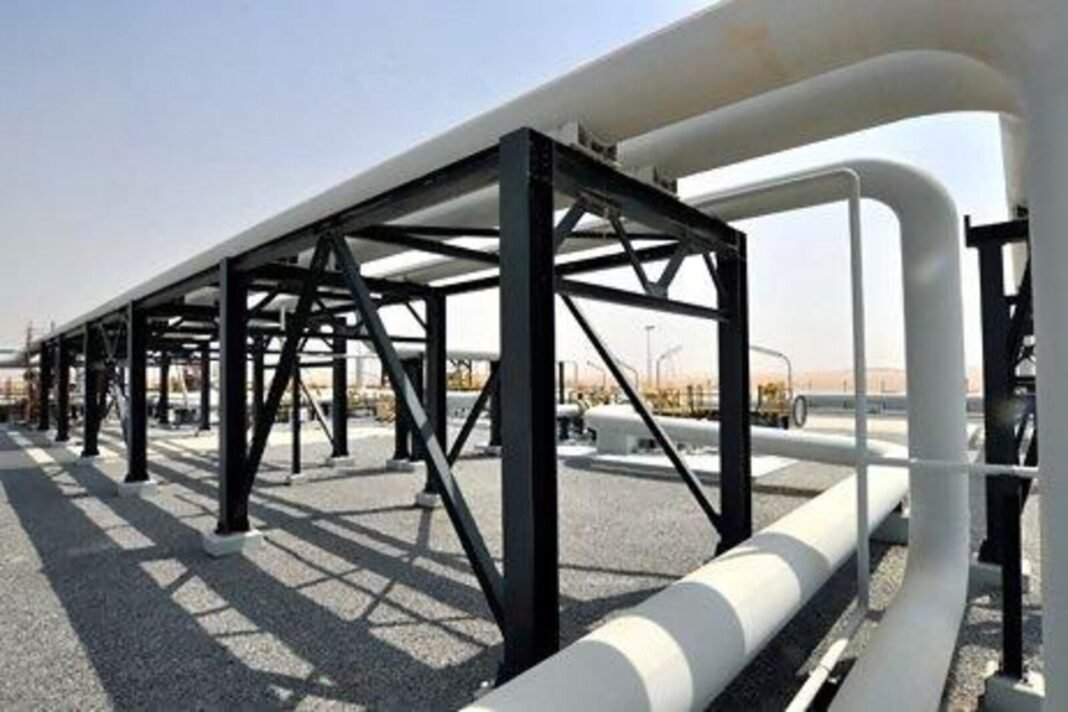 White above-ground crude oil pipelines on black steel supports at a desert pipeline facility in the UAE