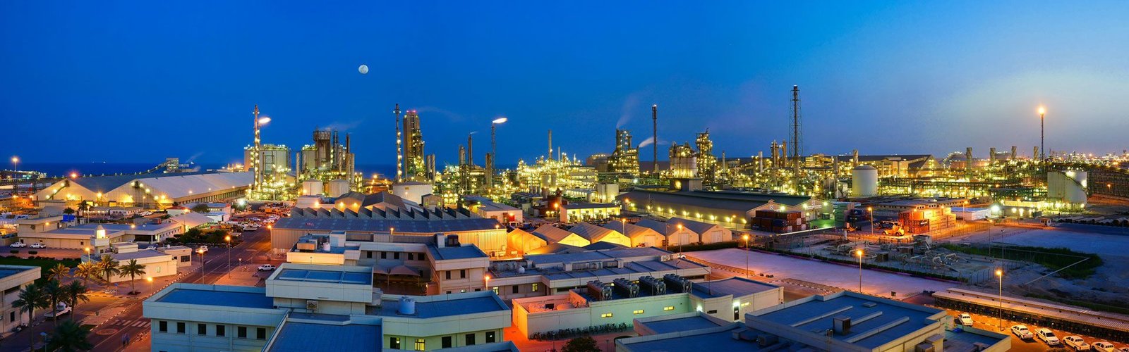 Qatar Fertiliser Company plant and office buildings lit up at dusk under a deep blue sky