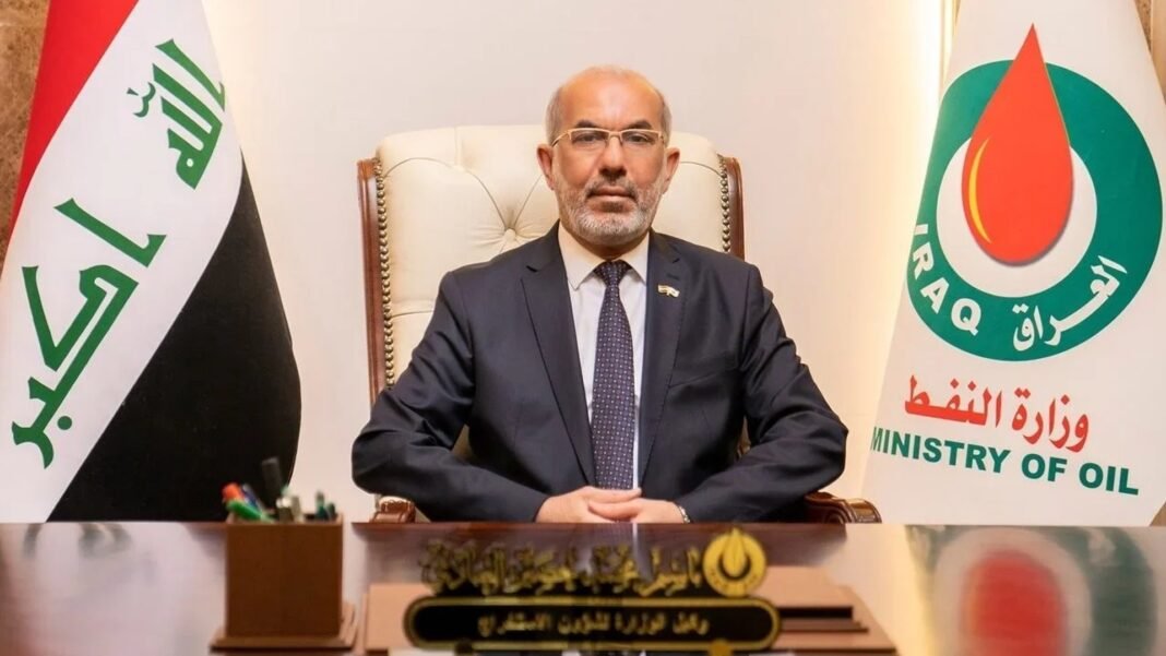 Iraqi Oil Minister Bassem Mohammed Khudair seated at a desk between the Iraqi flag and a Ministry of Oil flag