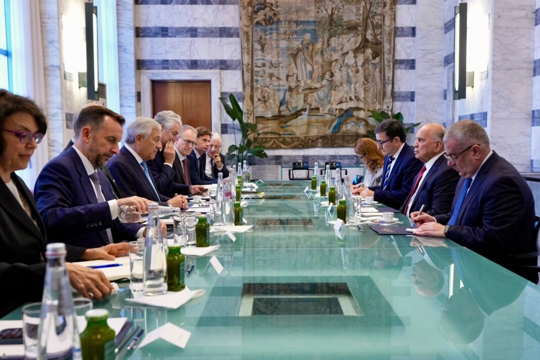 Iraqi and Italian officials sit facing each other across a long glass table in a marble meeting room