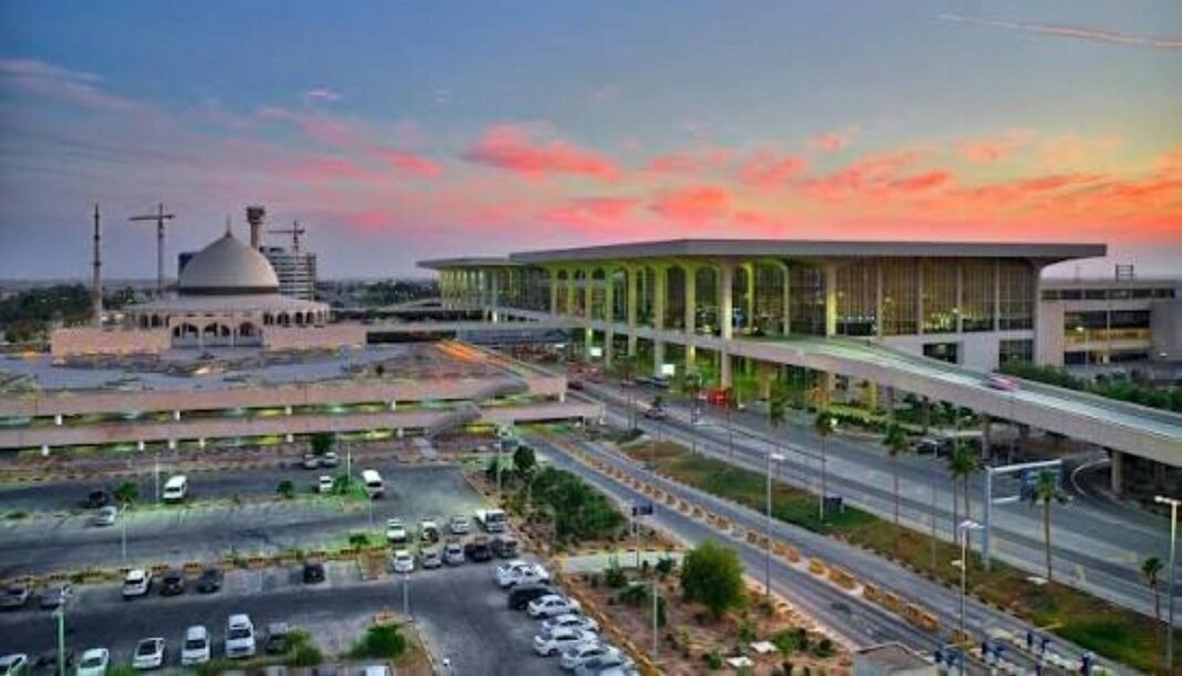 Terminal building and mosque dome at King Fahd International Airport in Dammam at sunset, with roads and a parking lot in front