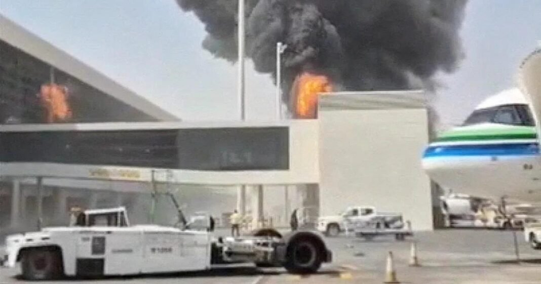 Black smoke and flames rise above a terminal building at King Khalid International Airport in Riyadh as an airliner stands at a gate