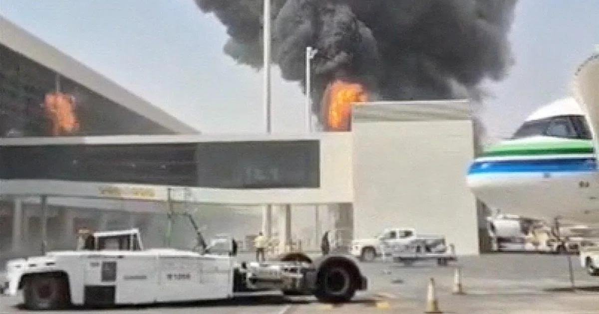 Black smoke and flames rise above a terminal building at King Khalid International Airport in Riyadh as an airliner stands at a gate