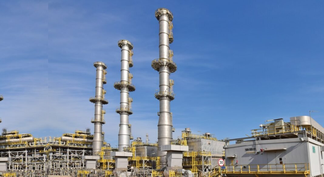 Tall processing columns and units at Kuwait National Petroleum Company's Mina Al-Ahmadi refinery under a blue sky