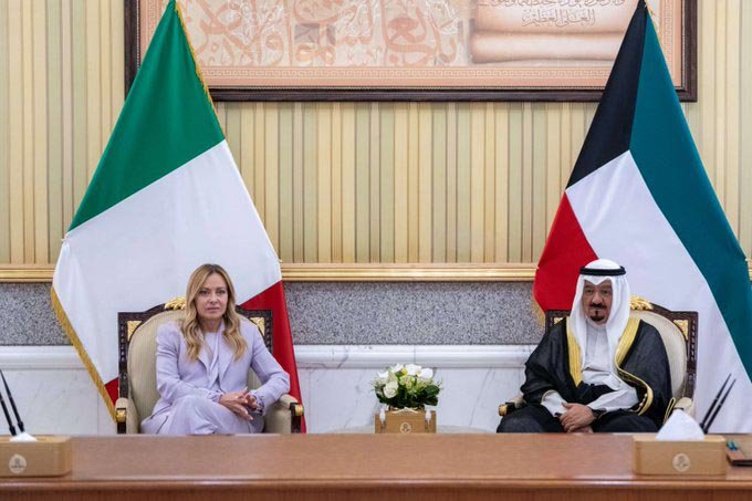 Italian Prime Minister Giorgia Meloni seated beside a Kuwaiti official in front of Italian and Kuwaiti flags