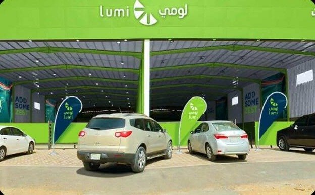 Cars parked outside a Lumi car rental branch with green Lumi signage and flags