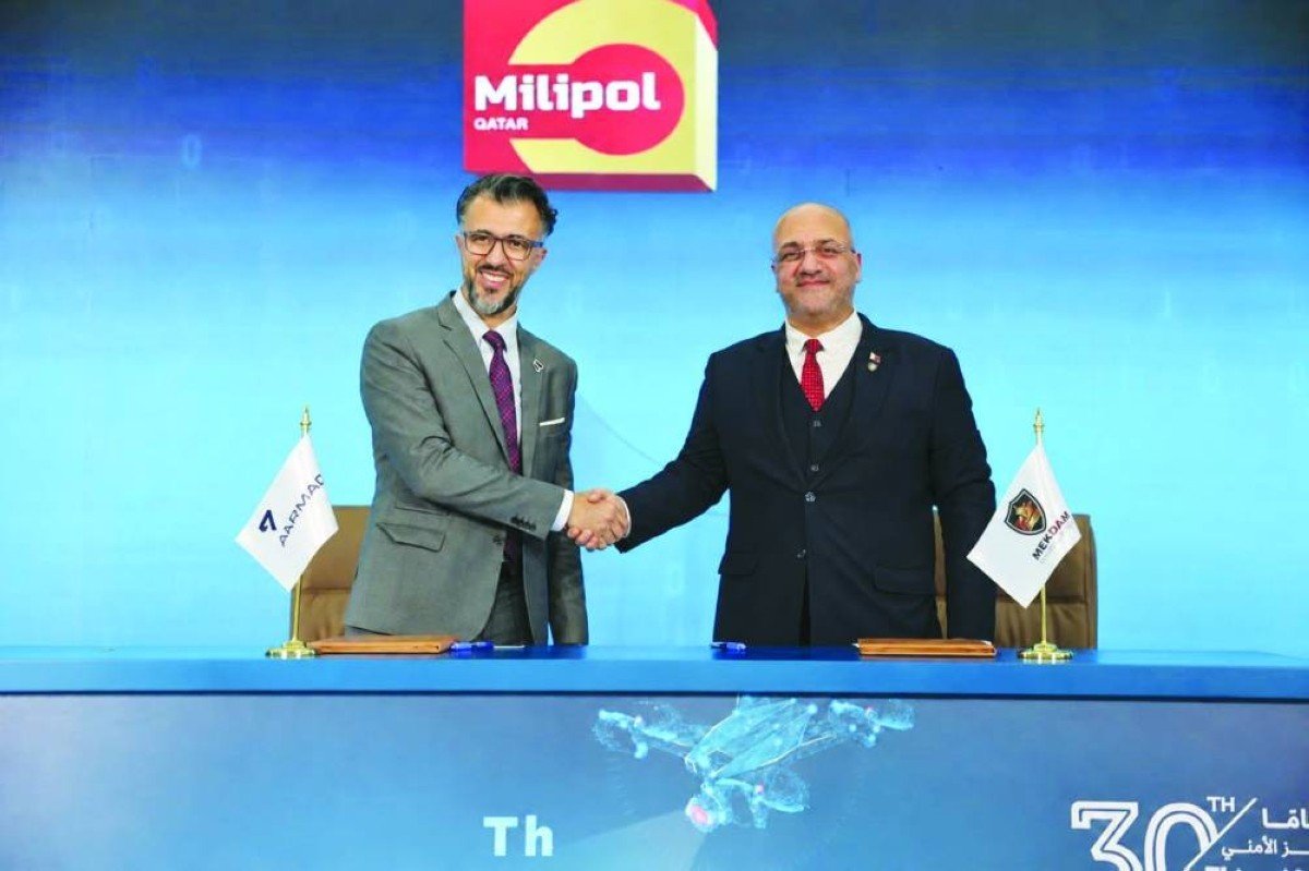 Two executives shake hands at a signing table at the Milipol Qatar exhibition in Doha