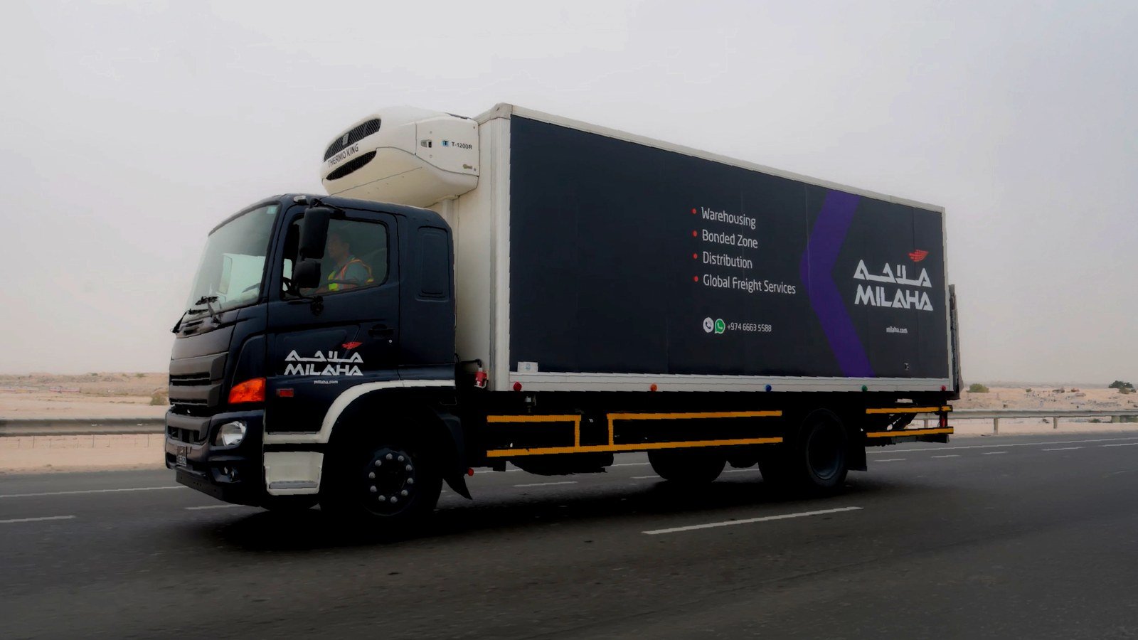 A Milaha-branded refrigerated logistics truck driving on a highway in Qatar
