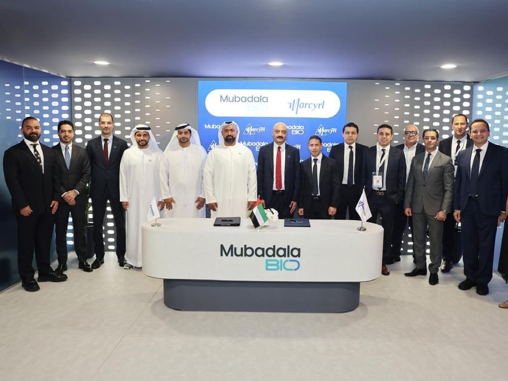 Mubadala Bio and Marcyrl Group executives standing behind a Mubadala Bio signing desk at the Abu Dhabi Future Health Summit