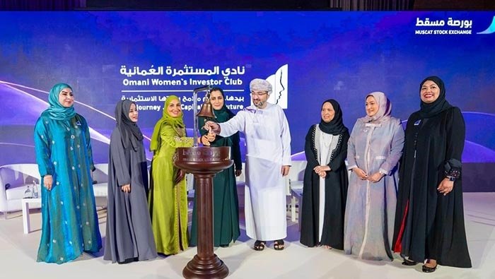 Members of the Omani Women's Investor Club and a Muscat Stock Exchange official at a bell-ringing ceremony on stage