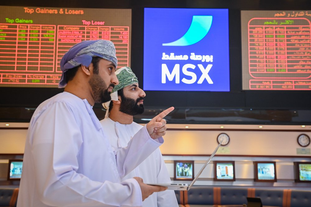 Two investors look at trading screens on the floor of the Muscat Stock Exchange
