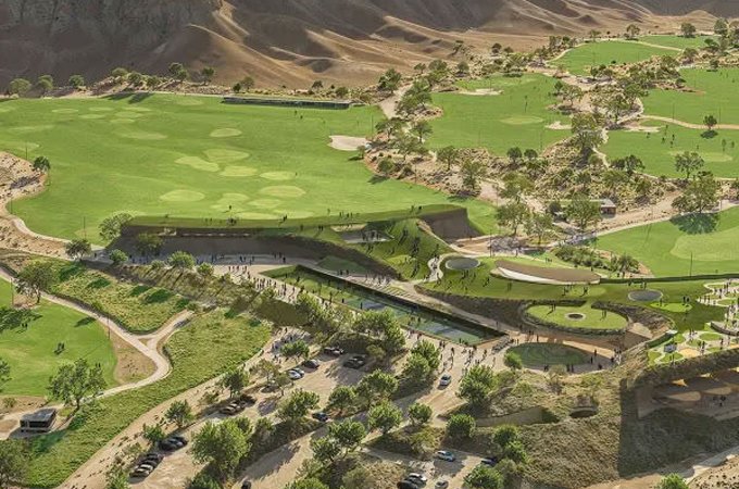 Aerial view of The National Golf Club in Qiddiya City with green fairways, a clubhouse and car parks below desert cliffs