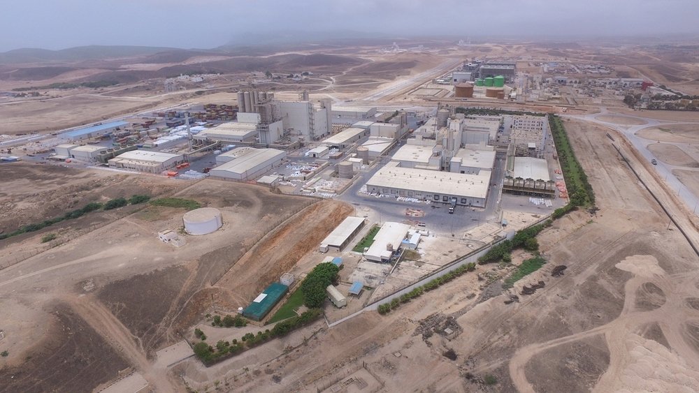 Aerial view of factories and warehouses in an industrial area in Oman with desert hills behind