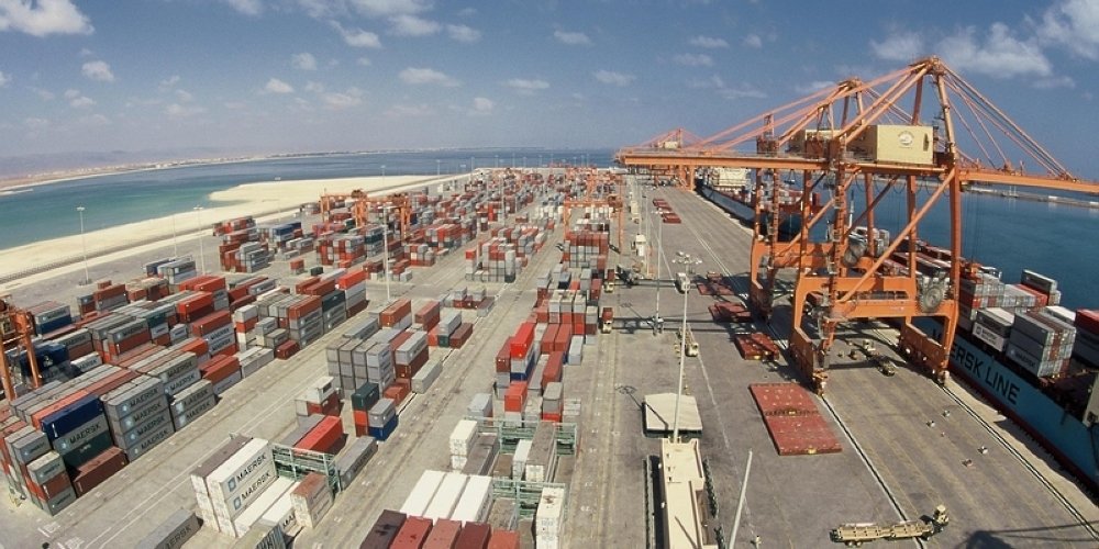 Gantry cranes and stacked shipping containers at a container terminal on the Omani coast
