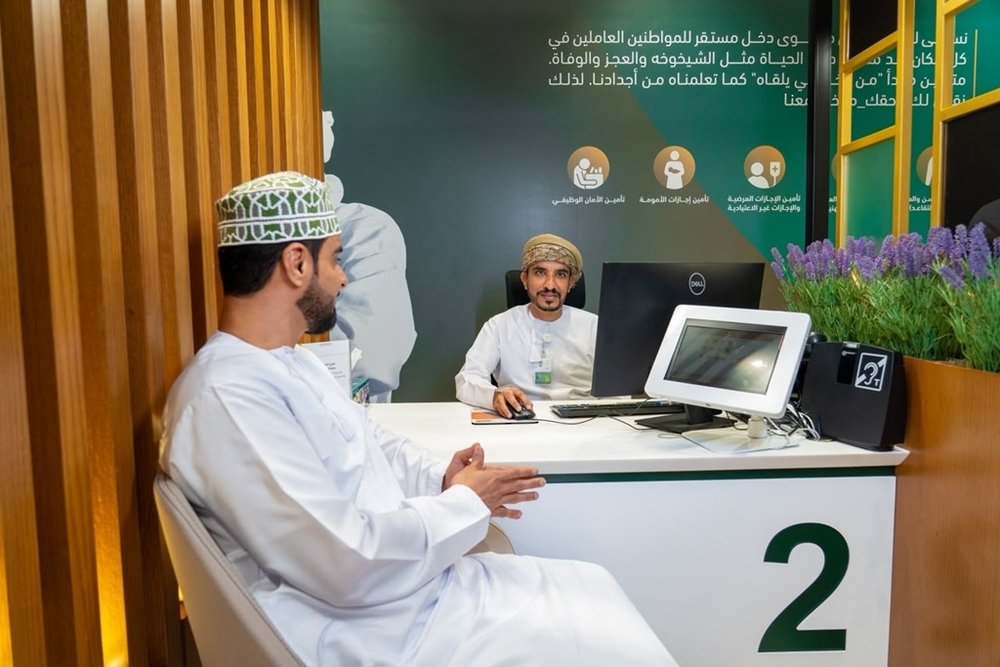 An Omani man speaks with an employee at a Social Protection Fund service counter