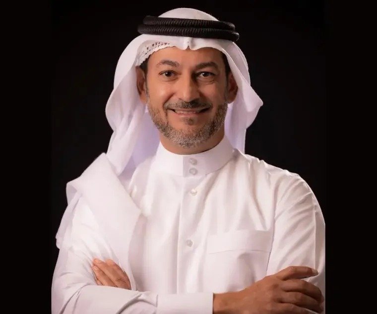 Ooredoo Group chief executive Aziz Aluthman Fakhroo in white thobe and ghutra, arms folded, against a dark background