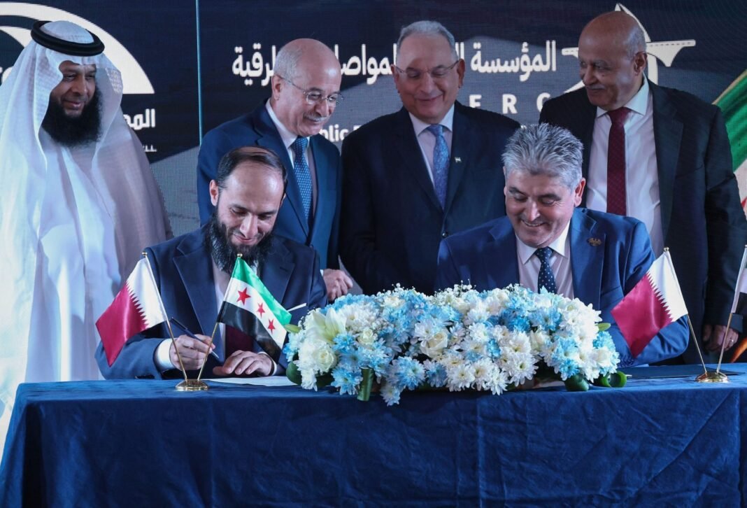Officials sign a road rehabilitation contract at a table with Syrian and Qatari flags in Damascus