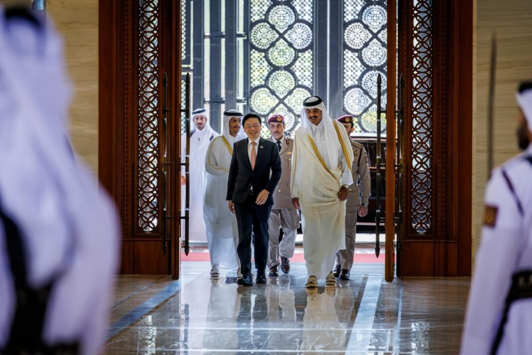 Qatar's Amir and Singapore's Prime Minister walk through an ornate doorway past an honor guard in Doha