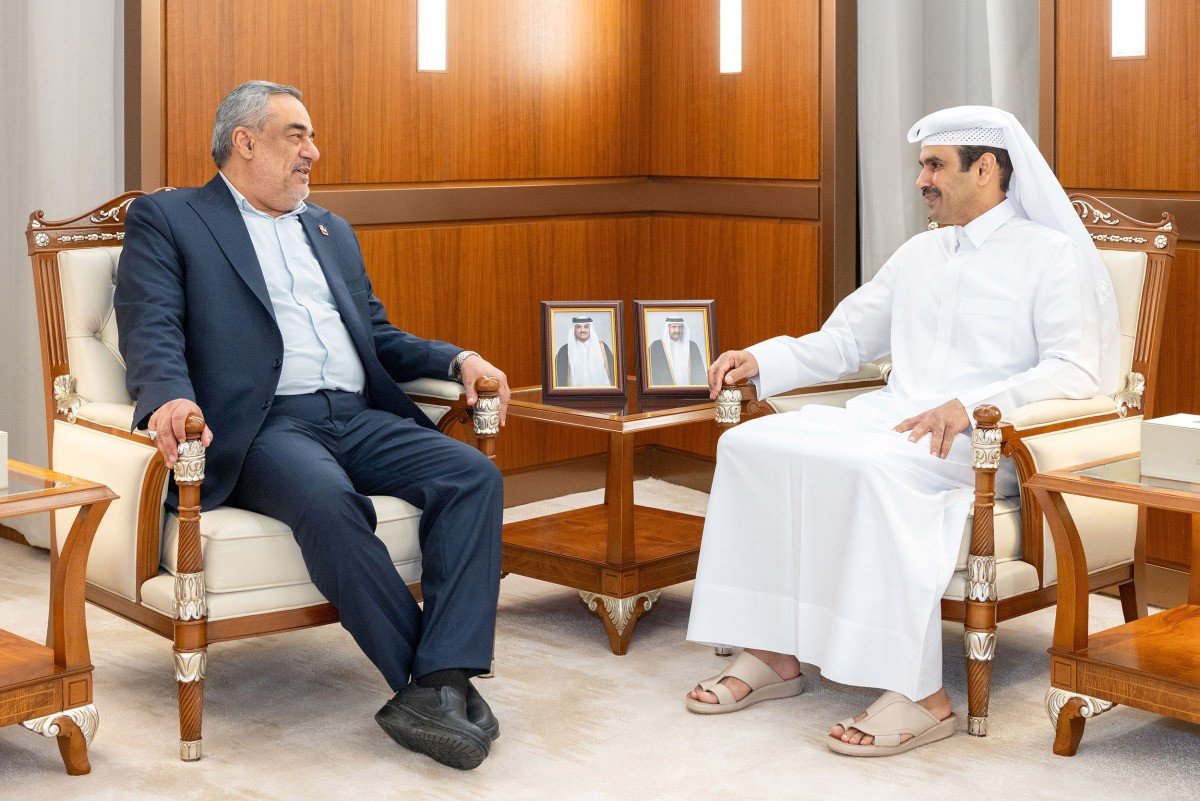 Qatar's energy minister Saad Sherida Al-Kaabi in white thobe seated opposite Iran's acting petroleum minister Hamid Bovard in a dark suit in a wood-paneled meeting room