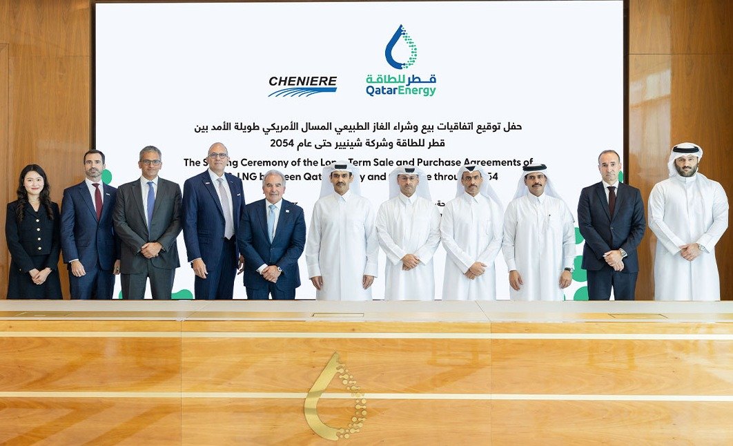 Group of QatarEnergy and Cheniere executives standing in a row in front of a screen announcing the LNG agreements signing ceremony