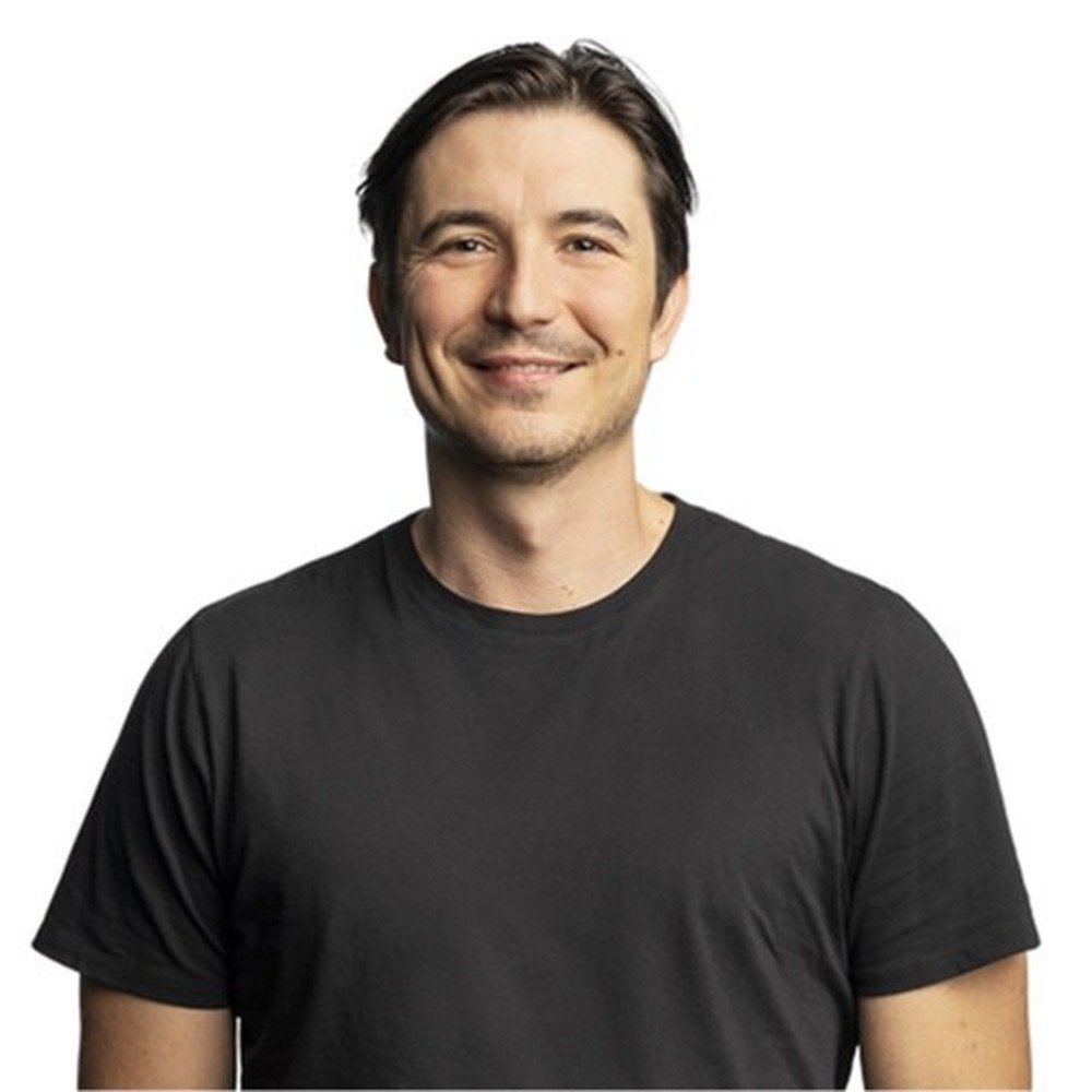 Robinhood chief executive Vlad Tenev smiling in a black T-shirt against a white background